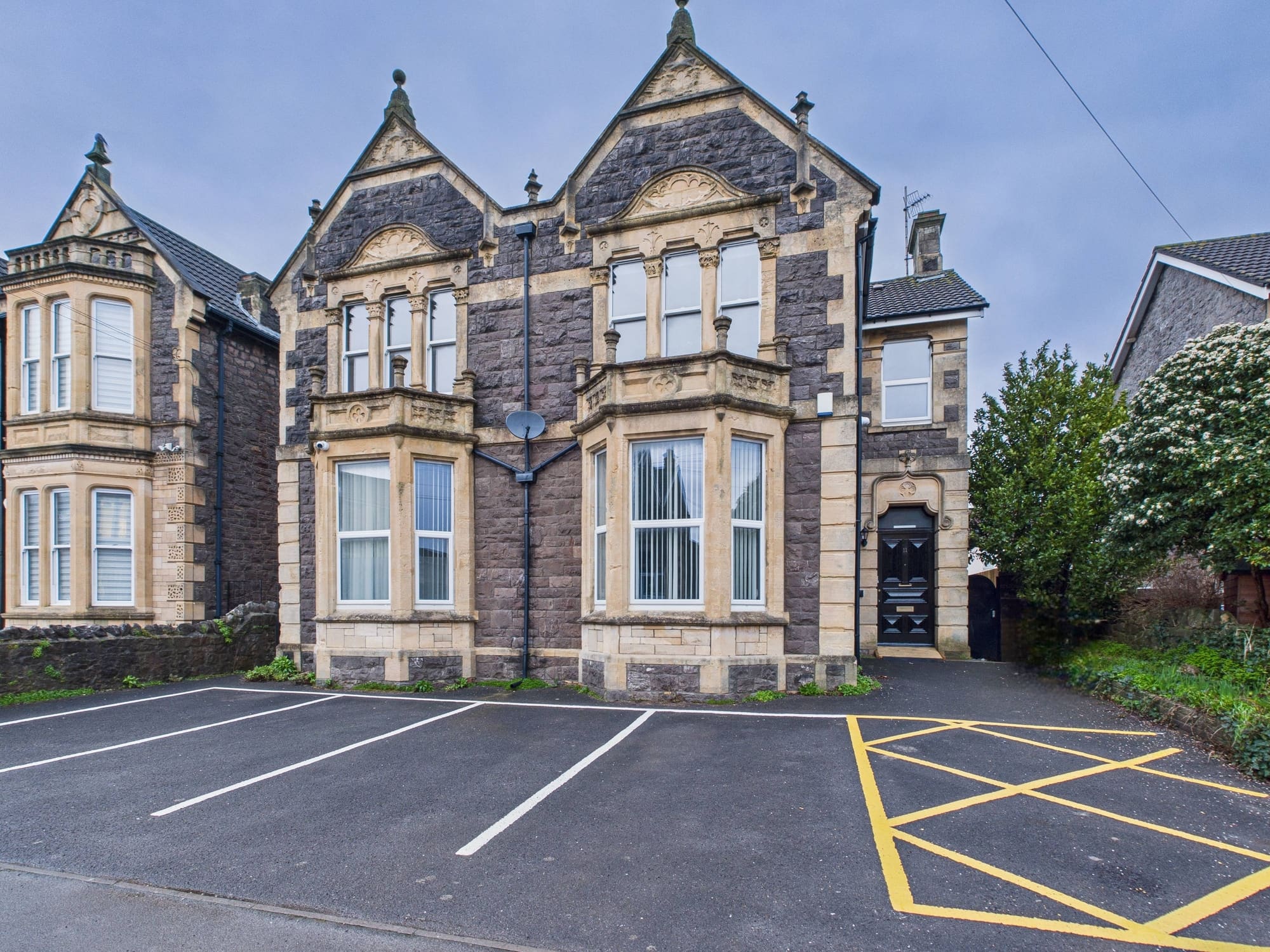 Beaconsfield House, a Victorian stone building with tall bay windows and its own parking, seen from the road.